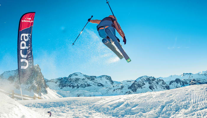 Skieur en l'air effectuant un saut freestyle dans un terrain enneigé aux Orres avec montagnes en arrière-plan