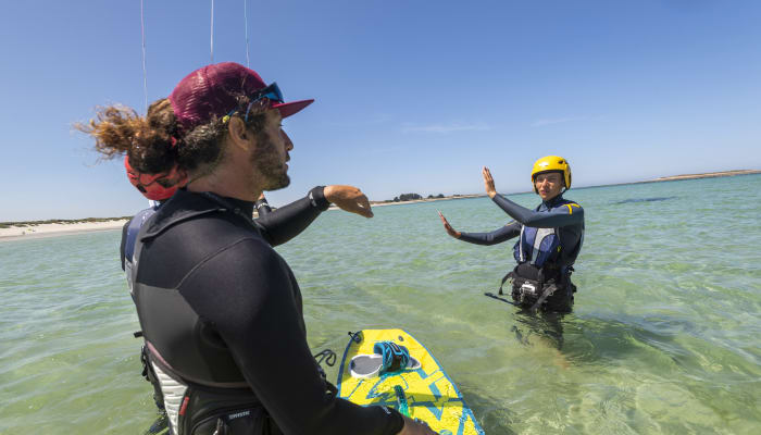 Moniteur de kitesurf enseignant à un élève en mer avec planche et équipement de sécurité à Bénodet