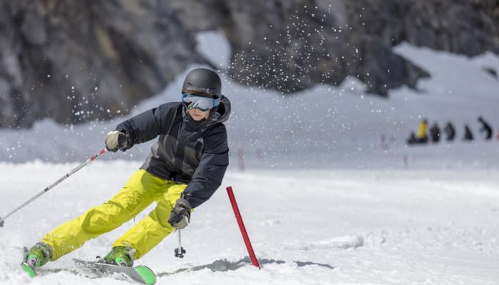Jeune skieur en compétition négociant un virage serré autour d'une porte de slalom aux Arcs