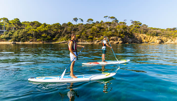Enfants pratiquant le surf en mer avec moniteur lors d'un séjour de débutant en eaux turquoise