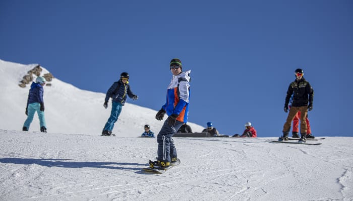 Groupe d'adolescents skiant et pratiquant le snowboard sur les pistes enneigées des Orres par beau temps