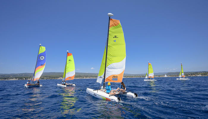 Enfants pratiquant la voile multisports dans le Golfe du Morbihan avec des voiliers colorés et flotteurs