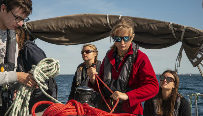 Adolescents en stage de voile niveau 3 FFV maniant cordages et voiles sur un bateau en mer bretonne