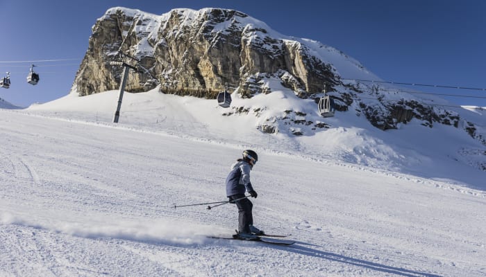 Jeune skieur débutant sur les pistes enneigées de Flaine avec télécabines et falaises rocheuses en arrière-plan