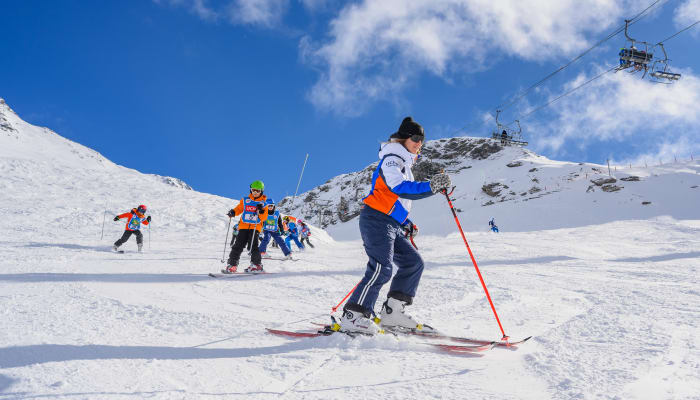 Jeunes skieurs débutants en cours de ski à Val Cenis sur pente enneigée avec moniteur et paysage montagneux