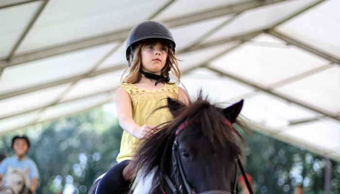 Enfant montant un poney noir avec casque d'équitation lors d'un stage équestre en Bretagne