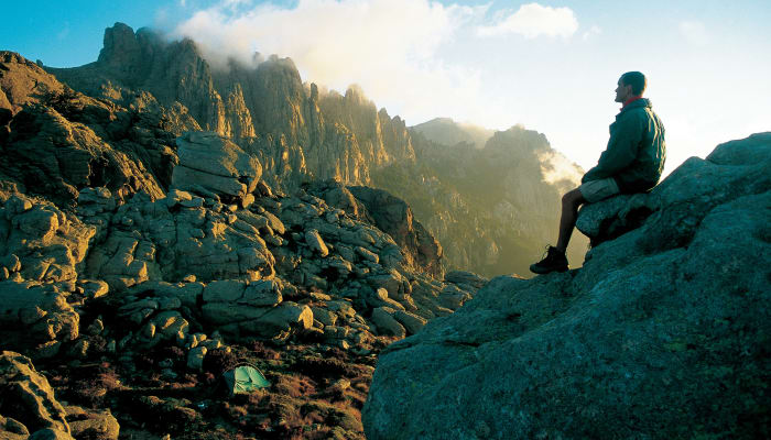 Randonneurs sur les crêtes rocheuses des Aiguilles de Bavella en Corse avec vue panoramique sur la chaîne montagneuse du GR20 Sud
