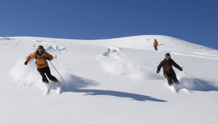 Skieurs experts en descente hors-piste à la Vallée Blanche sur pentes enneigées avec ciel bleu