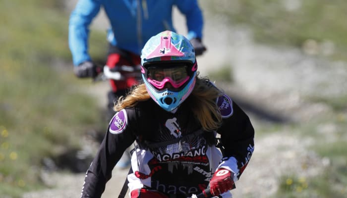 Jeune rider en VTT de descente avec casque et lunettes de protection sur un sentier de montagne à Serre Chevalier