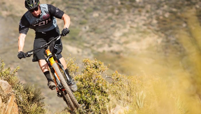 Cycliste en VTT enduro franchissant un terrain rocheux en montagne avec technique et équilibre
