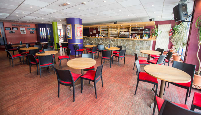 Espace d'accueil du centre UCPA Grand Serre Chevalier avec tables, chaises et bar de restauration