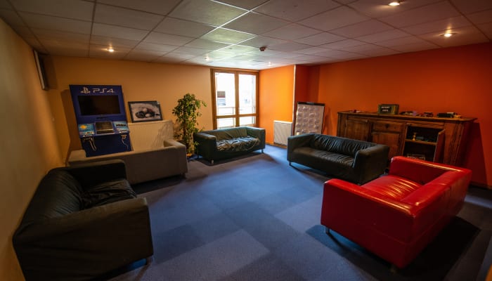 Espace détente du centre UCPA Grand Serre Chevalier avec canapés, console de jeux et salon de loisirs