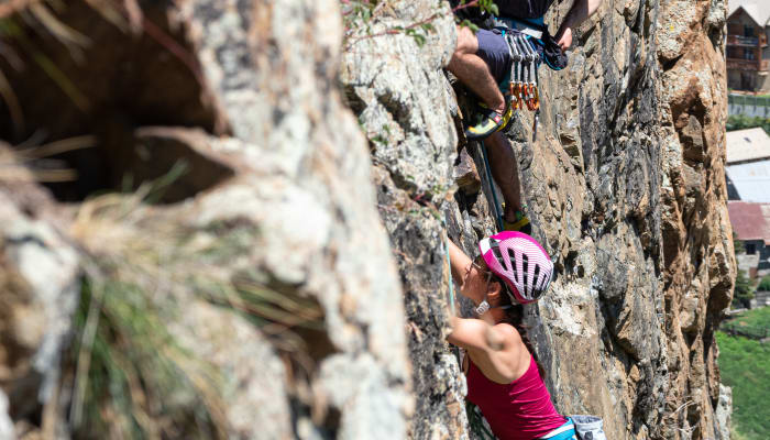 Grimpeur en escalade sur une falaise rocheuse à Serre Chevalier avec équipement de protection et casque