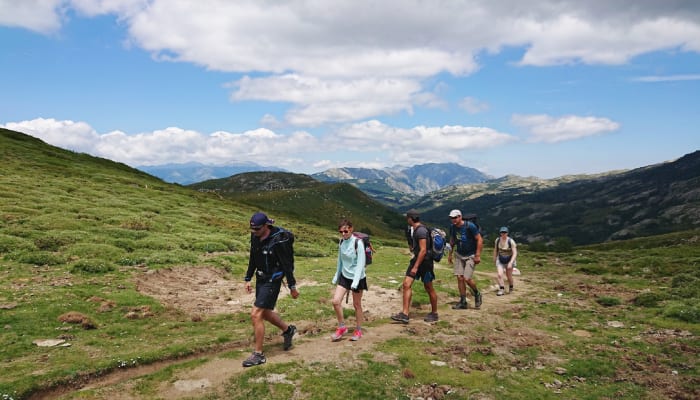 Groupe de randonneurs en montagne dans la vallée du Louron avec paysage pyrénéen et sommets enneigés