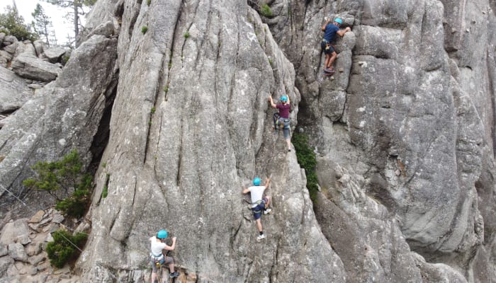 Groupe de grimpeurs pratiquant la via ferrata sur paroi rocheuse en Corse avec équipement de sécurité