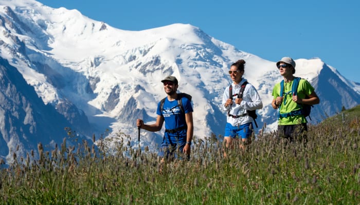 Groupe de randonneurs en trail running dans les Ecrins avec pic enneigé en arrière-plan par beau temps