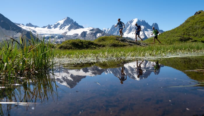 Randonneurs débutants sur sentier alpin du Mont-Blanc avec lac de montagne et pics enneigés en arrière-plan