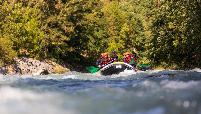 Groupe de rafters en gilets de sauvetage rouge naviguant les rapides d'une rivière de montagne entourée de forêt verdoyante