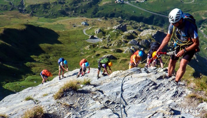 Groupe de randonneurs équipés en escalade sur paroi rocheuse en montagne lors d'un séjour multisports Audace