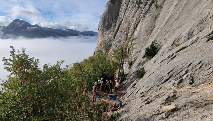 Groupe de grimpeurs au pied de falaises calcaires d'Orpierre avec vallée brumeus en arrière-plan