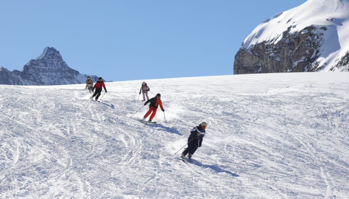 Groupe de skieurs en formation sur piste bleue à Serre Chevalier avec moniteur, paysage montagneux enneigé