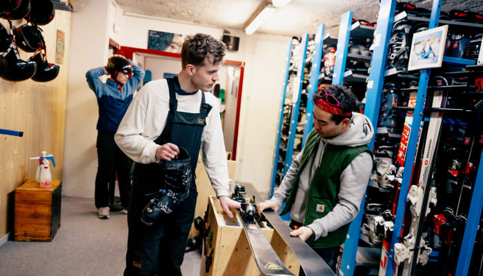 Moniteur de ski présentant une planche à un jeune client dans un magasin de location d'équipements de ski à Chamonix