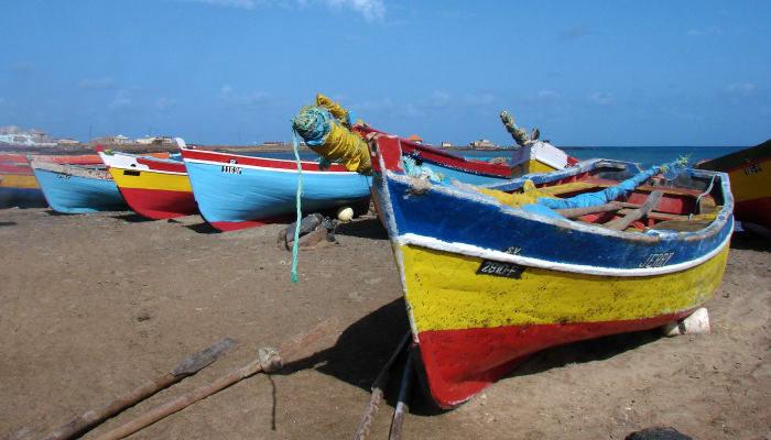Bateaux de pêche colorés alignés sur la plage de Santiago, île du Cap Vert, avec océan bleu et ciel dégagé