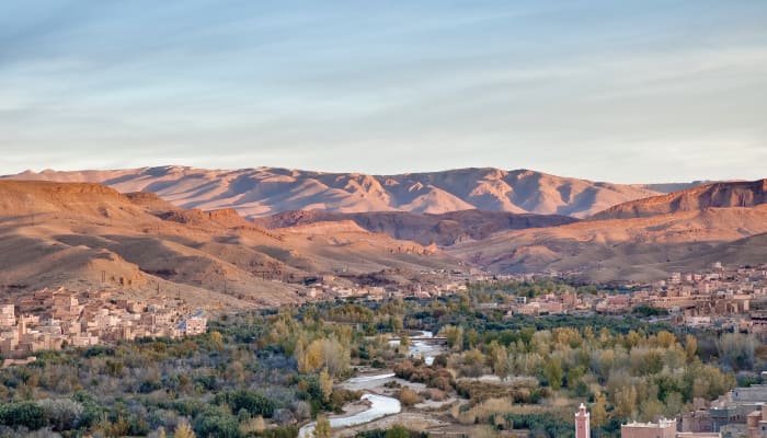 Vallée du Drâa avec djebels ocre, rivière sinueuse et oasis verdoyante dans le grand sud marocain