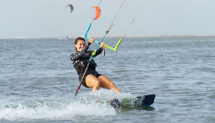 Kitesurfeur autonome naviguant sur l'eau avec cerf-volant orange et planche, séjour liberté 15 jours UCPA