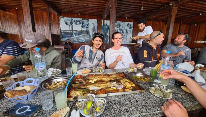Moniteur et élèves en cours de kitesurf partagent un repas convivial autour de plats traditionnels lors d'une session de perfectionnement
