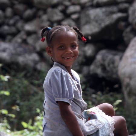 Enfant souriante devant rochers volcaniques à Santa Antao, Cap Vert