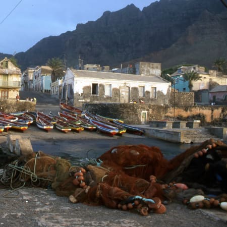 Village côtier de Cap Vert avec bateaux de pêche colorés, maisons blanches et falaises volcaniques en arrière-plan