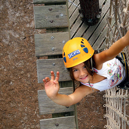 Enfant souriant portant un casque jaune lors d'une activité d'escalade en mur d'escalade MultiSports à Bombannes