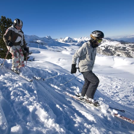 Groupe de skieurs en formation hors-piste sur versant enneigé avec panorama montagneux et vallée alpine