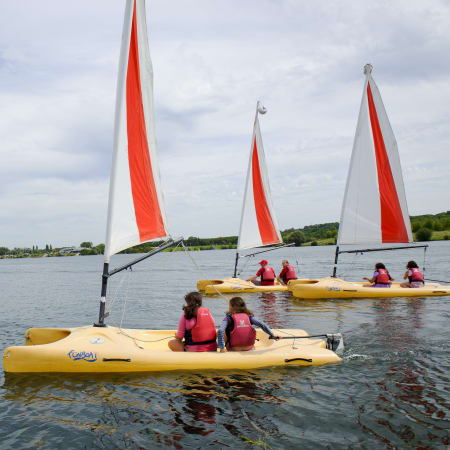 Enfants en gilets de sauvetage naviguant en voiliers jaunes avec voiles rouges et blanches sur l'eau du Golfe du Morbihan