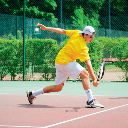 Jeune joueur en tenue jaune exécutant un coup de tennis sur court à Serre Chevalier