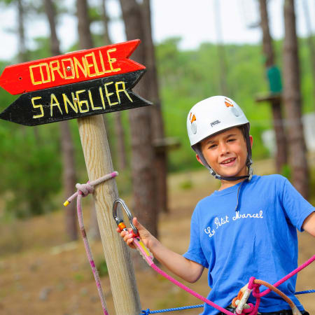 Enfant souriante en tenue de via ferrata avec casque et baudrier à Bombannes, parcours multisports jeunesse