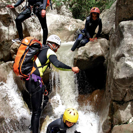 Enfants en équipement de canyoning descendant une cascade entre des rochers au Parc national du Mont Perdu