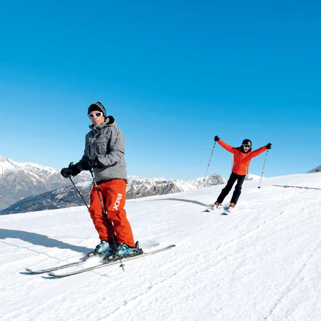 Jeunes skieurs débutants en séjour aux Orres sur piste enneigée avec montagnes en arrière-plan