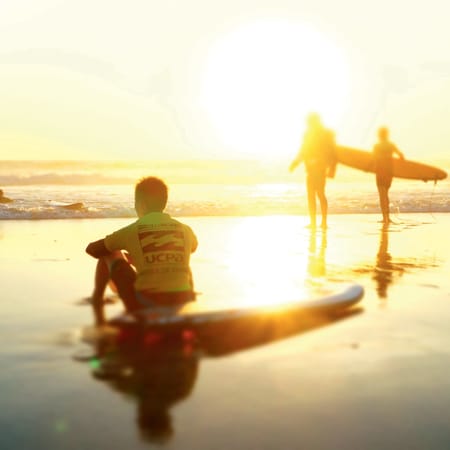 Jeunes surfeurs avec planches au coucher de soleil sur la plage de Martinique lors d'un séjour découverte