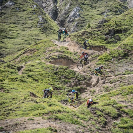Groupe d'enfants pratiquant le VTT et multisports sur les pentes vertes de La Plagne en colonie