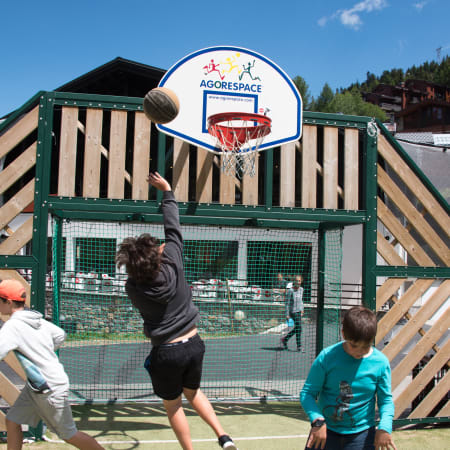 Enfant tirant au panier de basket Multi'Ride à la Plagne 1800, structure de jeu en bois et filet vert