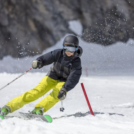 Jeune skieur en compétition négociant un virage serré autour d'une porte de slalom aux Arcs