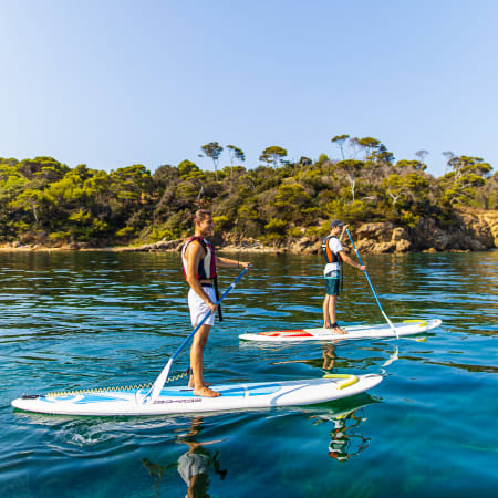 Enfants pratiquant le surf en mer avec moniteur lors d'un séjour de débutant en eaux turquoise