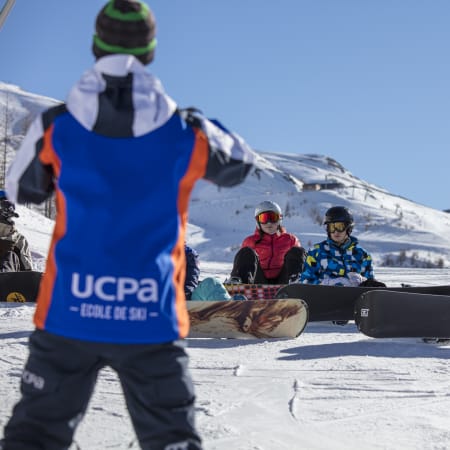 Groupe d'enfants et adolescents en séjour ski snowboard à Flaine avec moniteur et matériel de glisse sur neige