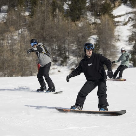Jeunes débutants en snowboard apprenant à rider sur les pistes enneigées des Orres avec instructeur
