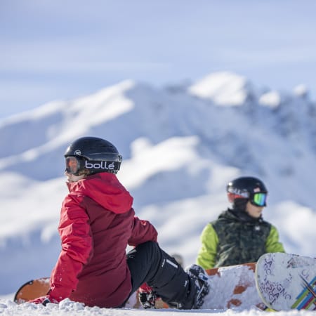 Jeunes skieurs et snowboarders en pause sur les pistes enneigées de Saint-Lary-Soulan avec vue sur les montagnes