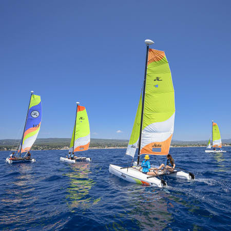 Enfants pratiquant la voile multisports dans le Golfe du Morbihan avec des voiliers colorés et flotteurs