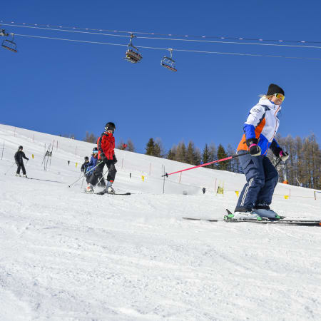Jeunes skieurs en cours de ski aux Arcs avec moniteur sur piste enneigée et remontées mécaniques