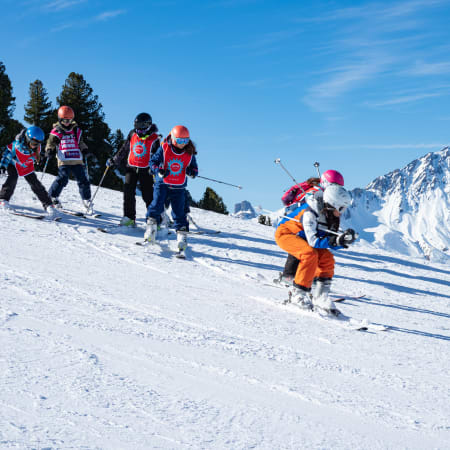 Groupe d'enfants en cours de ski aux Orres avec moniteur, pistes enneigées et montagnes alpines en arrière-plan